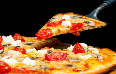 pizza funghi, tomatoes, feta cheese, mushrooms. A piece on a kitchen spatula. Traditional Italian cuisine.
