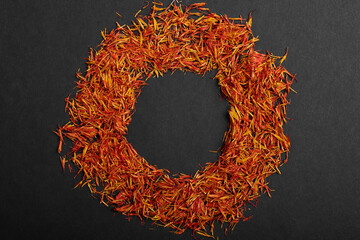 saffron lies in a circle on a black wooden background