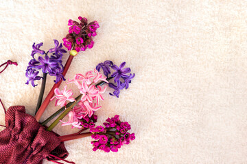 Fresh purple, blue and pink flowers bouquet on white plush fabric background. Top view. Copy space. Poster