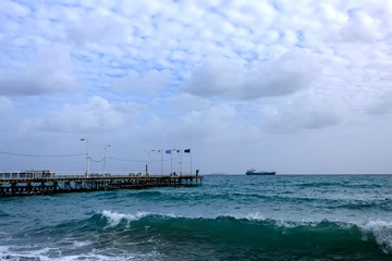 Zelfklevend Fotobehang Pier in Limassol Old Port in winter with wavy sea and cloudy sky, Cyprus  © Olga