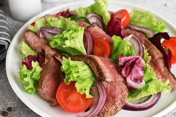 Salad with beef, lettuce and tomatoes on a concrete background.