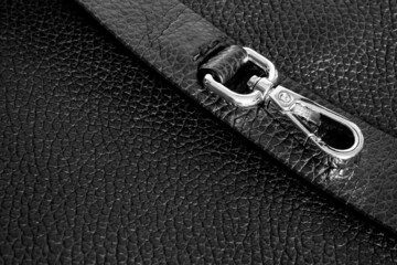 gold metal carabiner with ring on strap of black bag