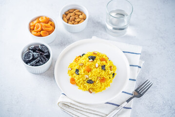 Turmeric basmati rice with dried apricots and prunes and almonds in a plate