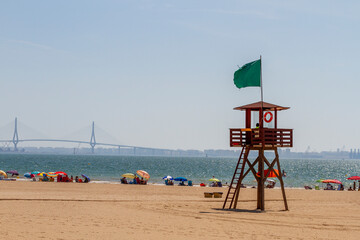 lifeguard in the surveillance beach tower with bathers bathing and sunbathing on the shore