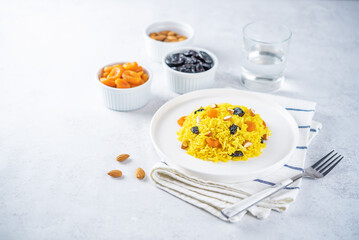 Turmeric basmati rice with dried apricots and prunes and almonds in a plate