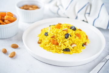 Turmeric basmati rice with dried apricots and prunes and almonds in a plate