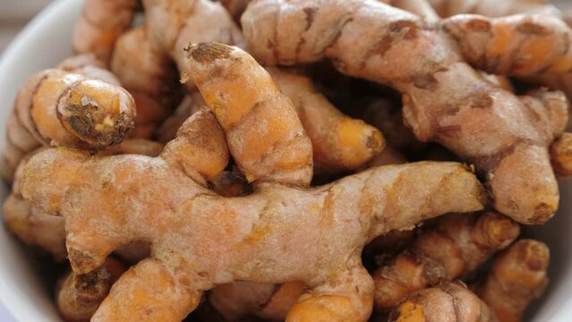 Roots of turmeric in plate on table. Rotating