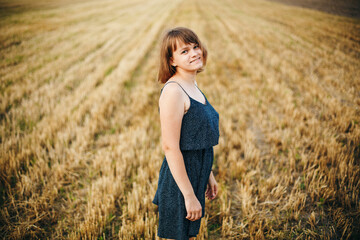 A beautiful girl and a field on which they threshed grain. Woman after harvest. Girl and yellow field
