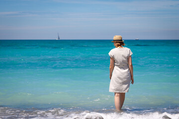 Kobieta w kapeluszu na turkusowej plaży