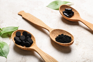 Spoons with different types of activated carbon on grunge background