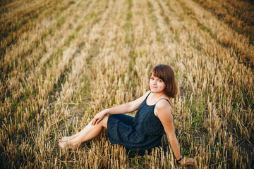 A beautiful girl and a field on which they threshed grain. Woman after harvest. Girl and yellow field
