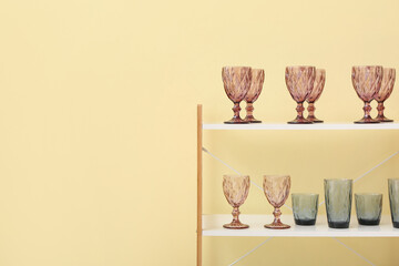 Different glasses on shelf unit near color wall