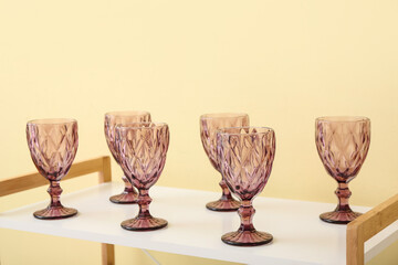 Glasses on shelf unit near color wall, closeup