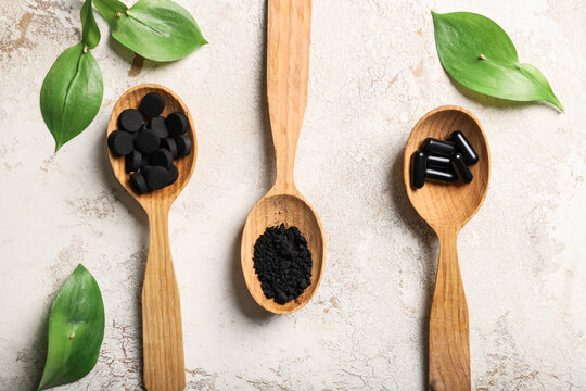 Spoons with different types of activated carbon on grunge background