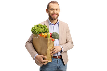 Young man holding a paper bag with vegetables and smiling