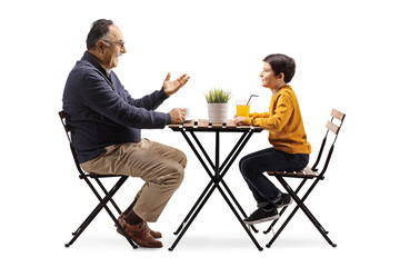 Grandfather sitting at a cafe table and talking to a grandson