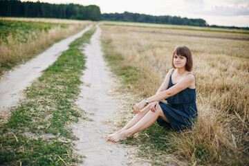 A beautiful girl and a field on which they threshed grain. Woman after harvest. Girl and yellow field

