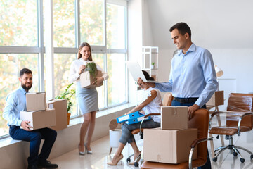 Young man with laptop in office on moving day