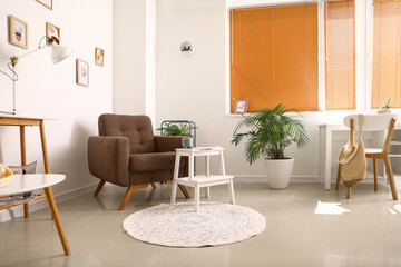 Interior of light living room with cozy armchair and white step stool