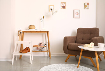 Wooden table and step stool with decor near light wall