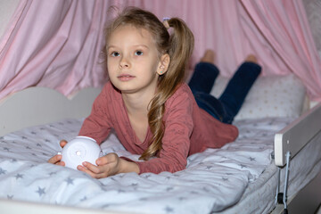 The girl has a small portable projector in her hands for watching movies