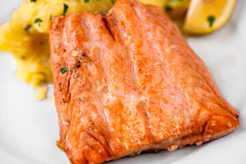 Salmon steak with mashed potato on white plate.