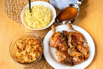 Baked chicken, stuffing, mashed potato and sauce on table.