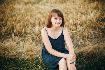 A beautiful girl and a field on which they threshed grain. Woman after harvest. Girl and yellow field
