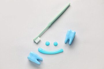 Smile made of toothpaste, brush and plastic teeth on light background