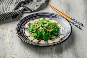 Chuka salad with peanut sauce on grey wooden table