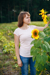 Beautiful girl and two lonely sunflowers in the field
