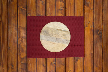 Top view of an empty wooden platter on a red napkin or dish towel on wooden table