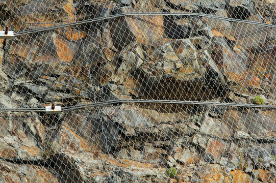 detail of a mesh rockfall barrier draped along