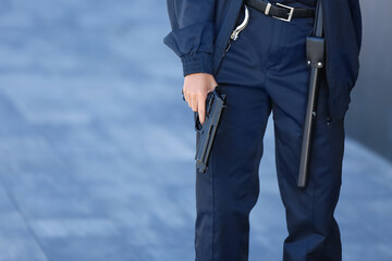Female security guard with gun near building outdoors, closeup