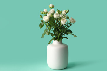 Vase with bouquet of beautiful roses on green background