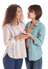 Happy lesbian couple with engagement ring on white background