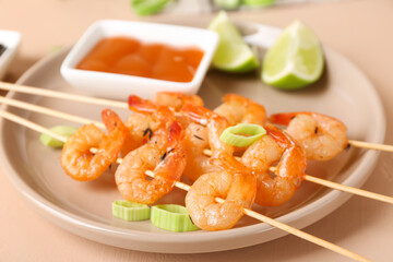 Plate with grilled shrimp skewers on beige background