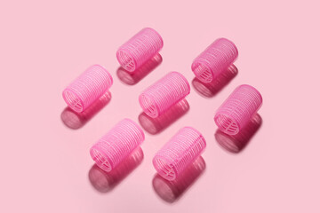 Set of hair curlers on pink background