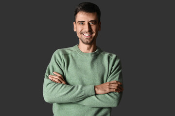 Handsome young man in knitted sweater on dark background