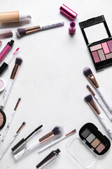 Frame made of different makeup products on light background