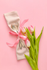 Fototapeta na wymiar Stylish cutlery with tulip flowers on pink background