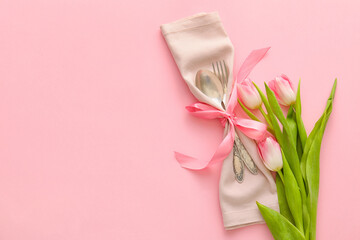 Stylish cutlery with tulip flowers on pink background