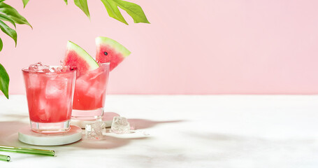 Fresh summer cocktail watermelon juice with ice in a two glass and glass straw on pink background. Layout for wide banner with space for text.