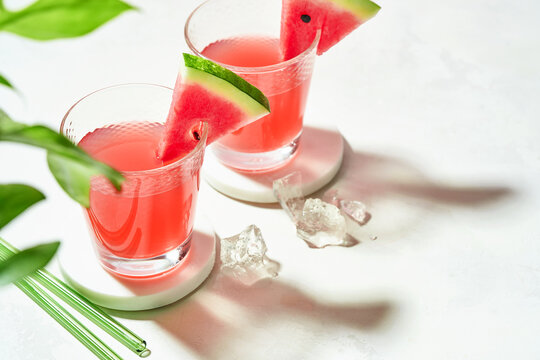 Fresh summer cocktail watermelon juice with ice in a two glass and glass straw on white background with copyspace.