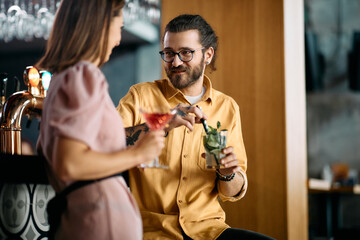 Happy man and his girlfriend drink cocktails while talking on date in cafe.