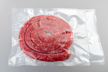 Italian sausage (salsiccia) in vacuum packed sealed for sous vide cooking isolated on grey...