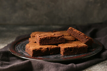 Plate with pieces of tasty chocolate brownie on grey background