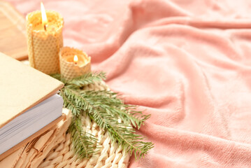 Closeup view of books, fir tree branch and burning candles on bed