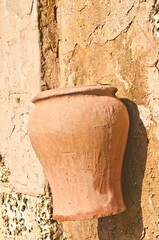 front view, medium distance of a clay planter attached to a stone wall on a tropical afternoon