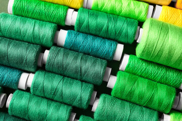 Spools with green threads as background, closeup